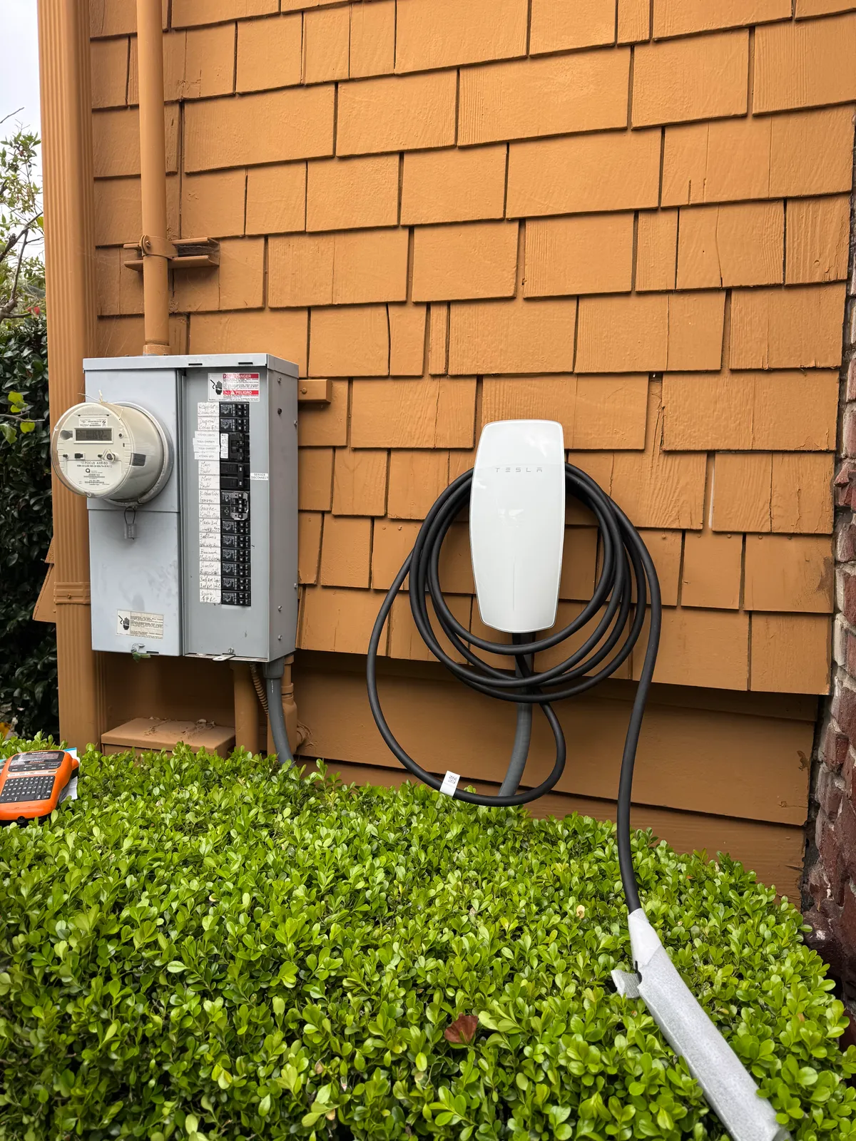 Complete EV charger installation showing Tesla charger and electrical panel — East Bay Electrical