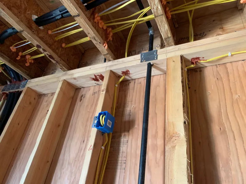 Romex wiring and blue outlet box in open framing — East Bay Electrical